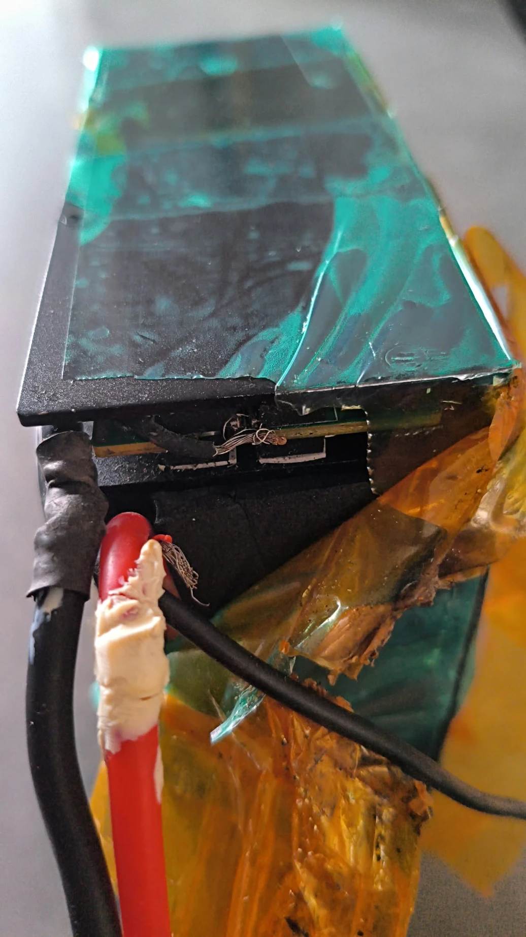 Loose conductor strands beside torn wrapping and red and black leads.