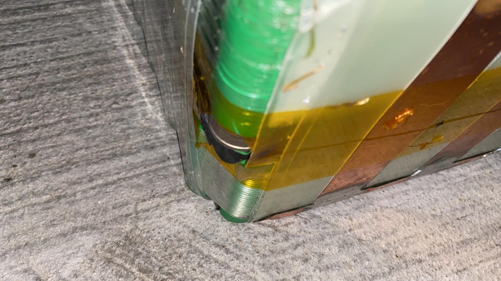 Amber wrapping lifting at the edge of a green-cell assembly.