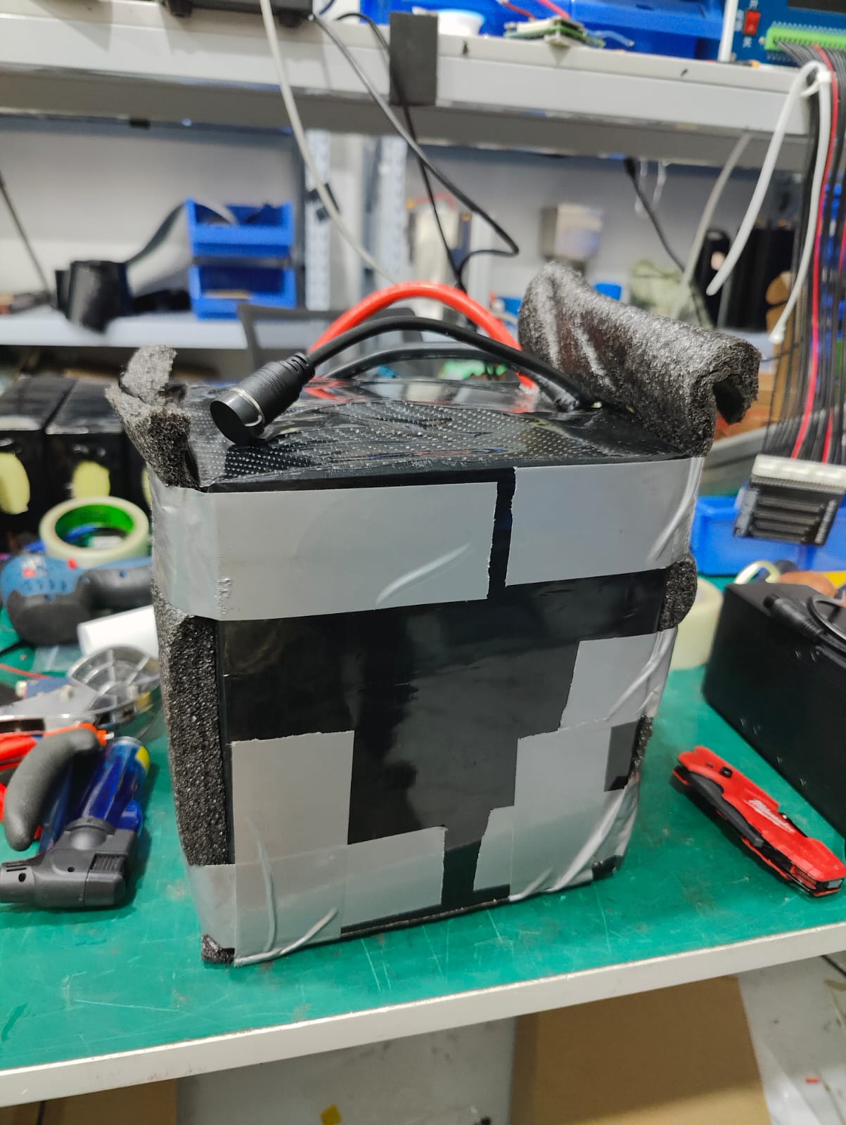 Overlapping grey and black tape and foam cover the assembly.