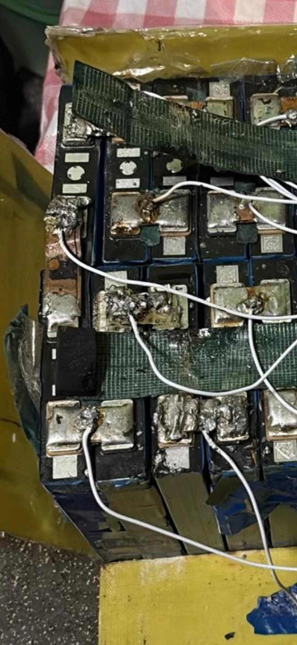 Lumpy solder and dark spots on the cell connections, with mesh tape across the pack.