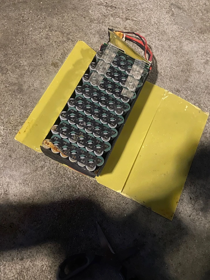 An opened cell assembly beside detached yellow panels.