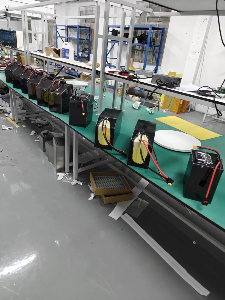 A long workbench lined with finished black battery packs.