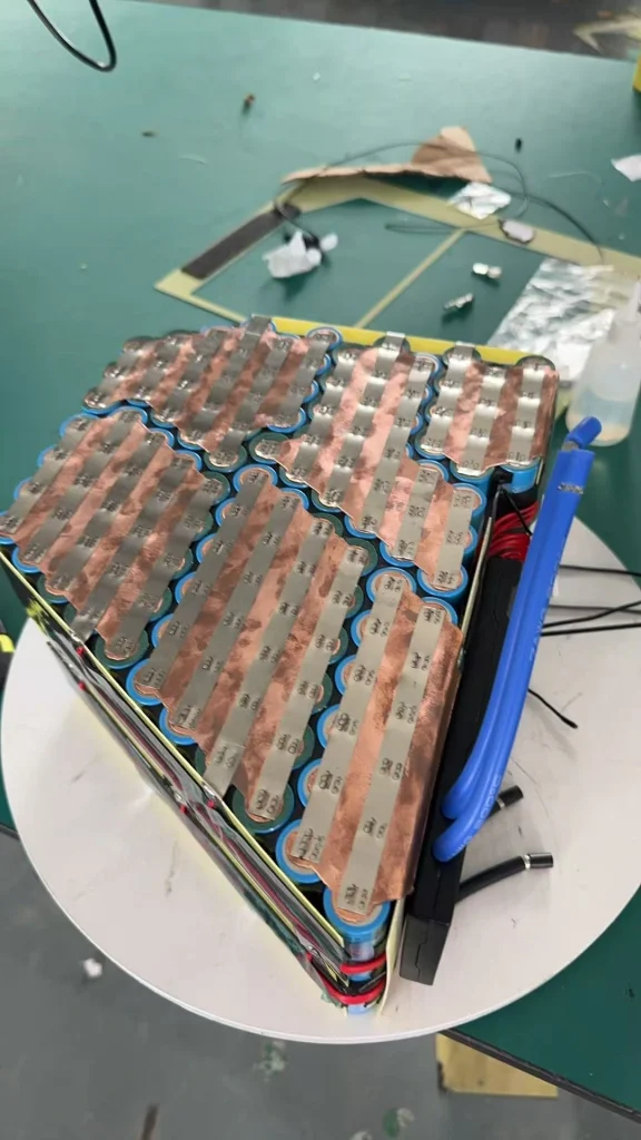 An angled multi-module cell assembly with shaped copper-coloured connections, on a turntable.