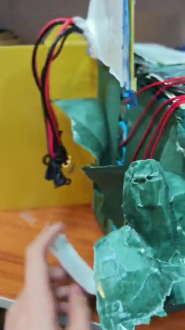 Torn green barley paper on the pack, with a bundle of red and black balance wires and their connectors hanging out