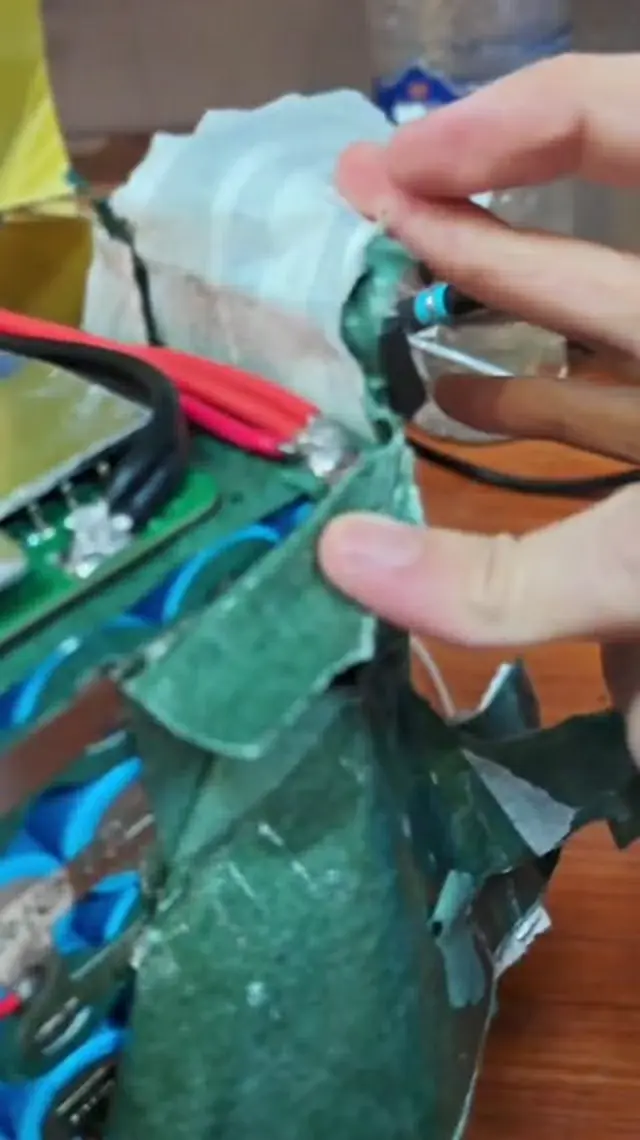 Barley paper being peeled back beside the BMS, where the thick red and black leads are soldered