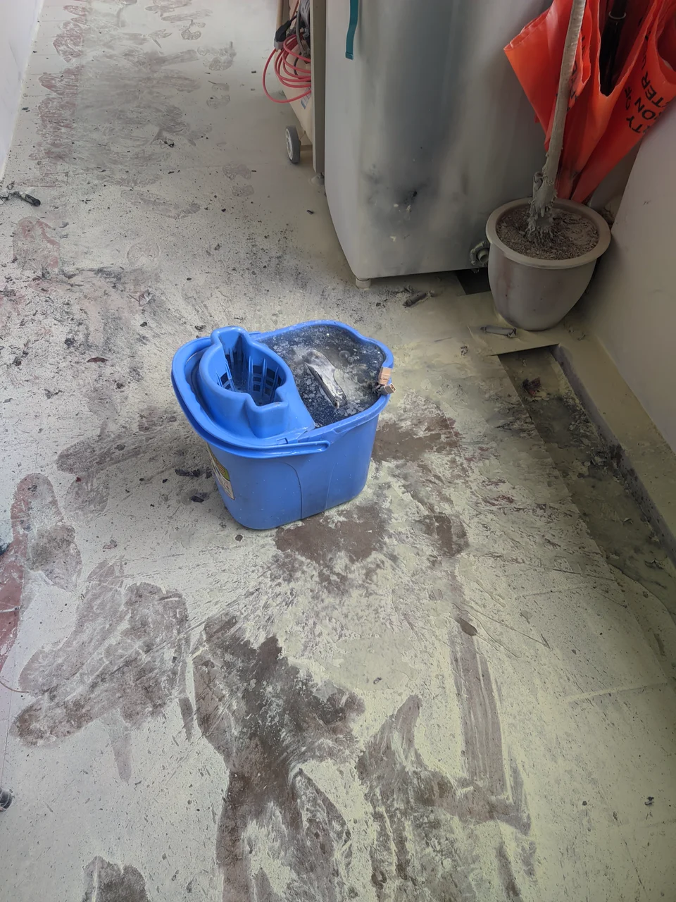 A blue mop bucket in an HDB corridor, extinguisher powder smeared across the floor