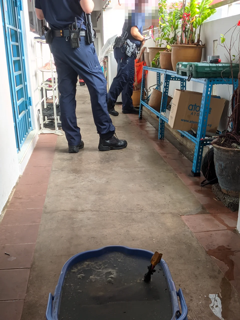 Uniformed officers standing in the corridor behind the bucket
