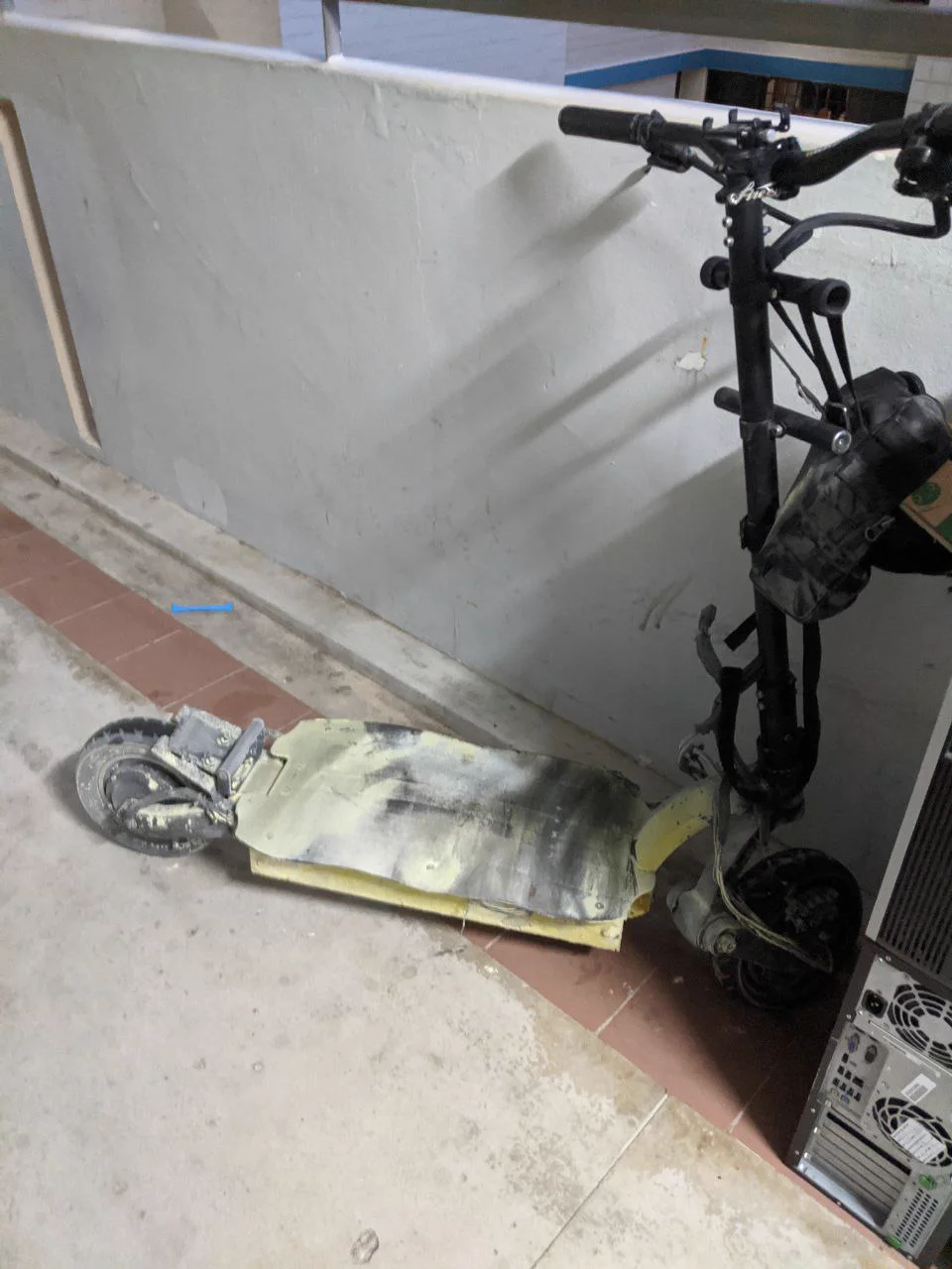 The burnt scooter frame against a wall