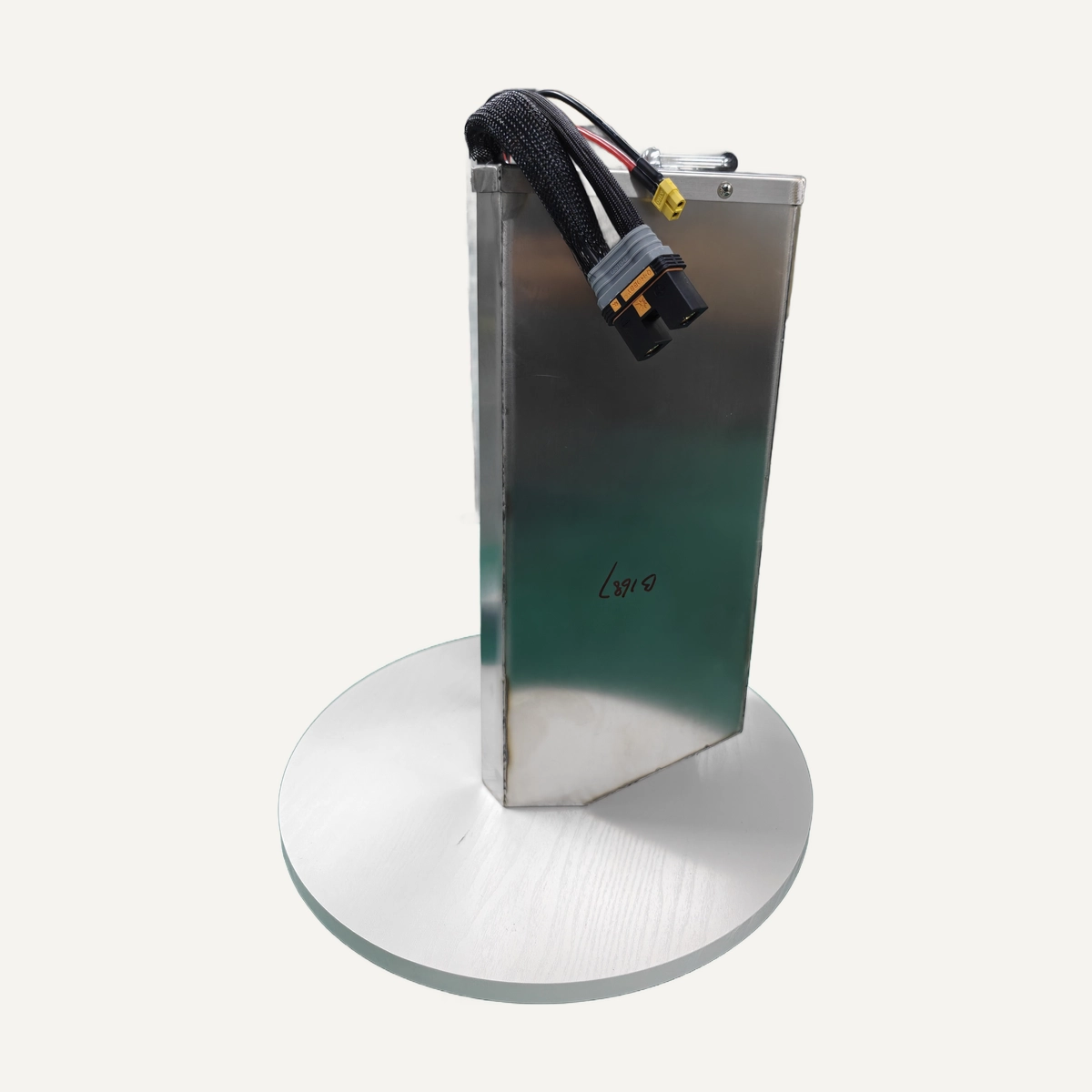 Shortened Honda CRF250 battery with silver casing and external leads, on a circular display stand.
