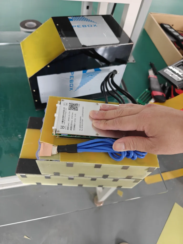 Open EM5 battery assembly with a protection board, blue wires and insulation.