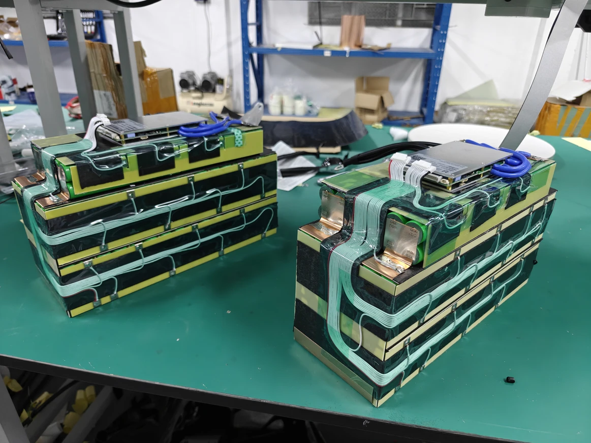 Two stepped battery modules showing insulation layers, routed wiring and boards on top.