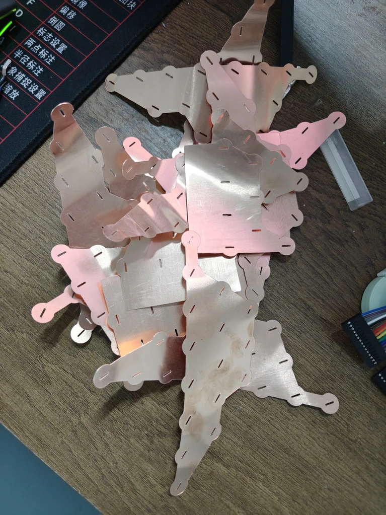 A pile of cut copper and nickel busbars on the bench