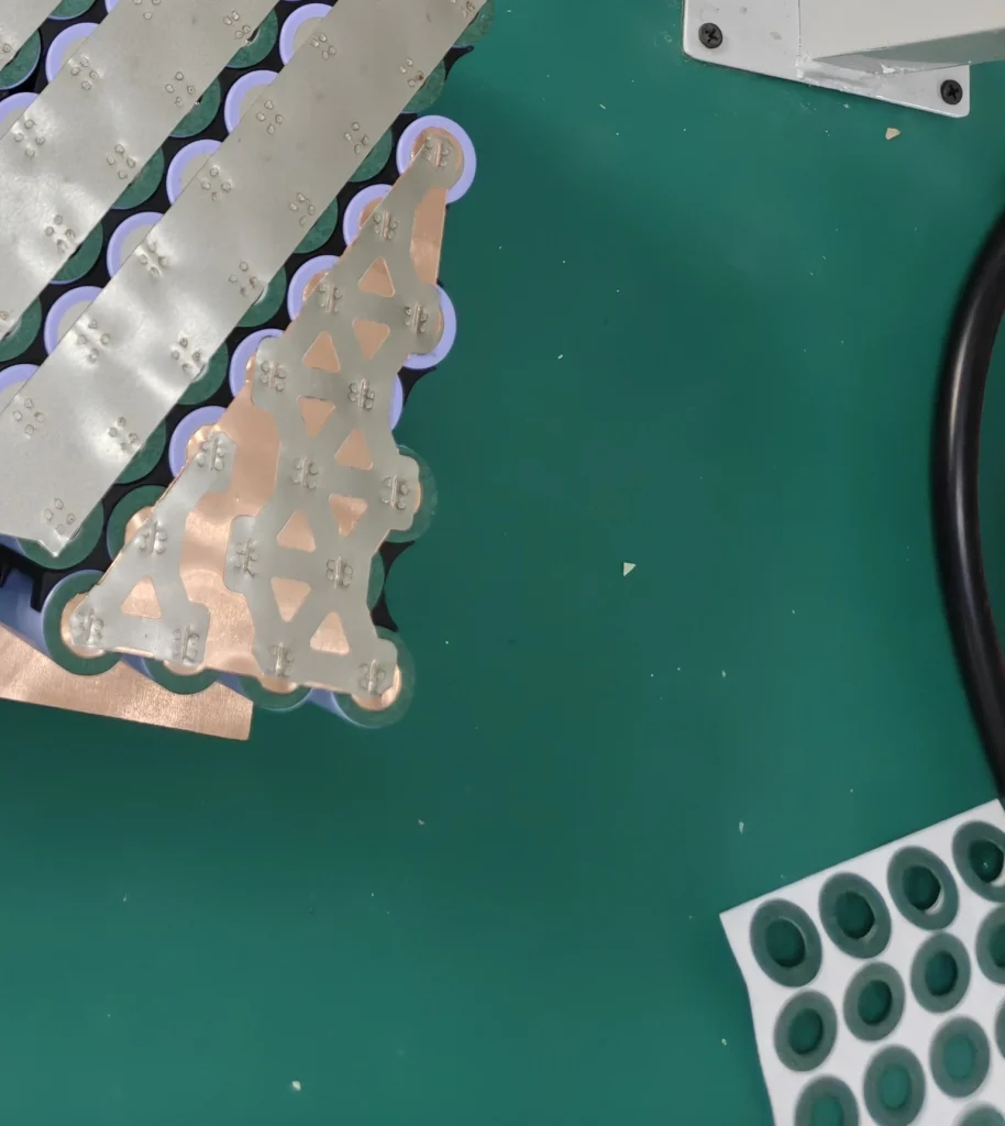 A sheet of green insulation rings beside a partly welded Razor module