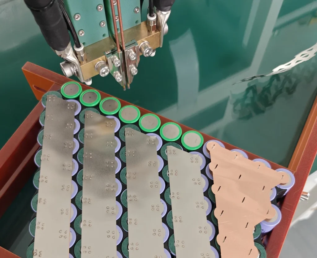 Spot welder above a Razor module with nickel strips and a copper plate on ringed cells