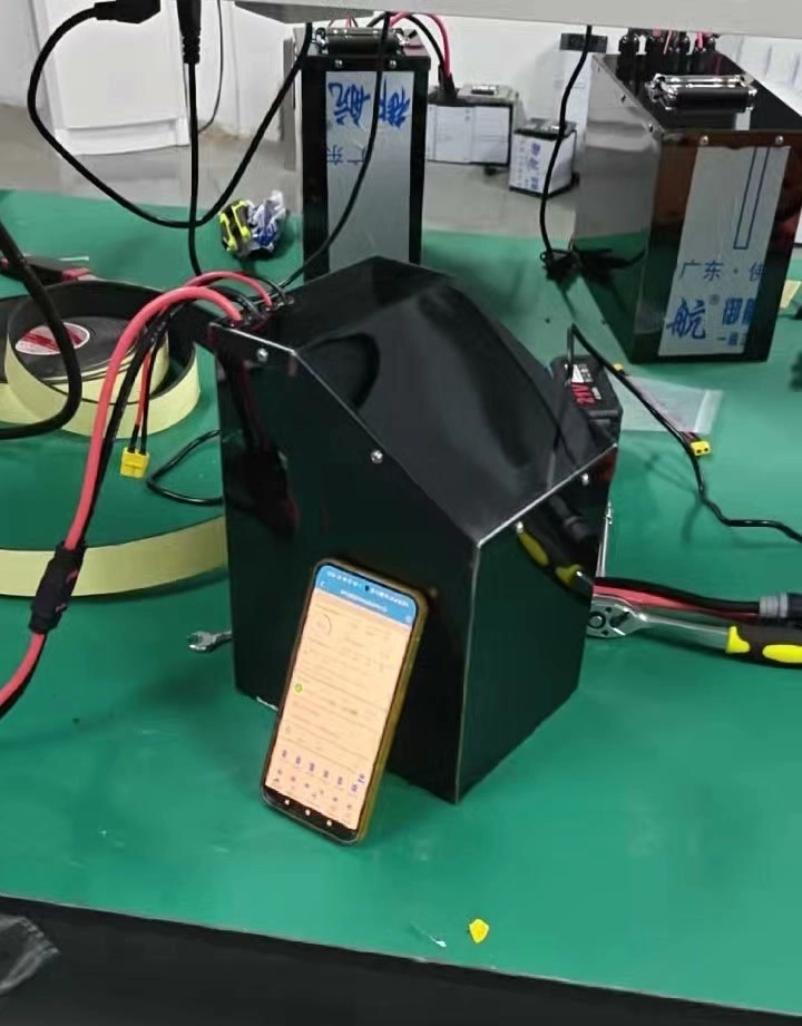 The finished Razor pack with test leads attached and its BMS app open on a phone