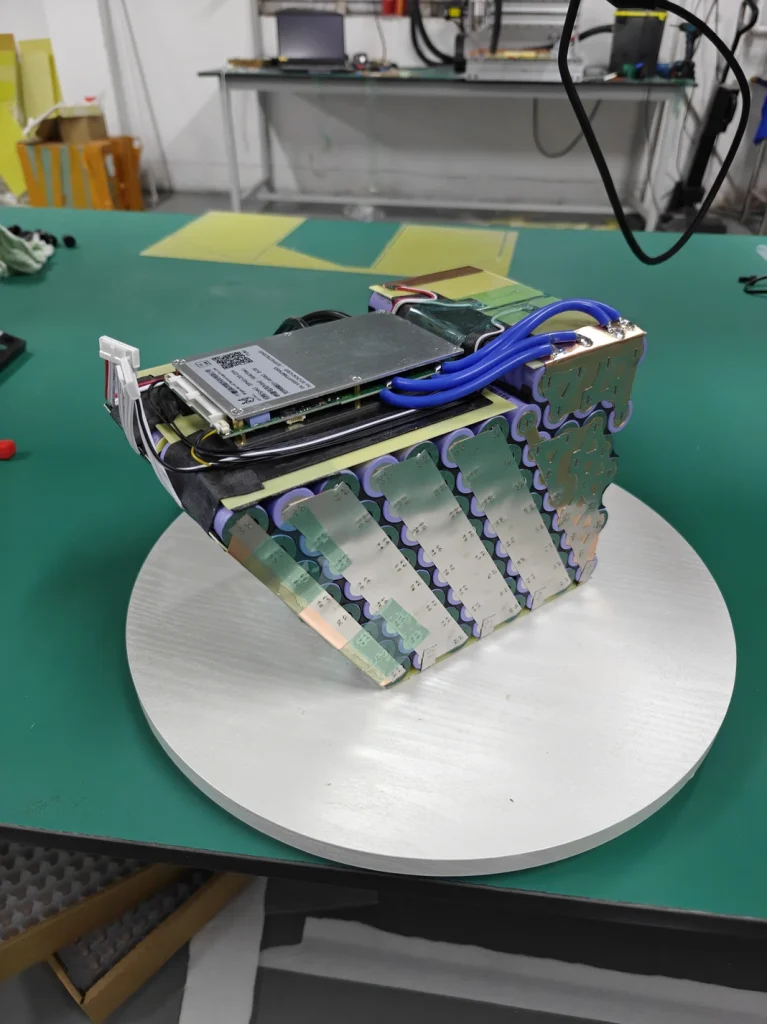 Open Razor battery assembly with visible cell connections, a circuit board and blue wiring.