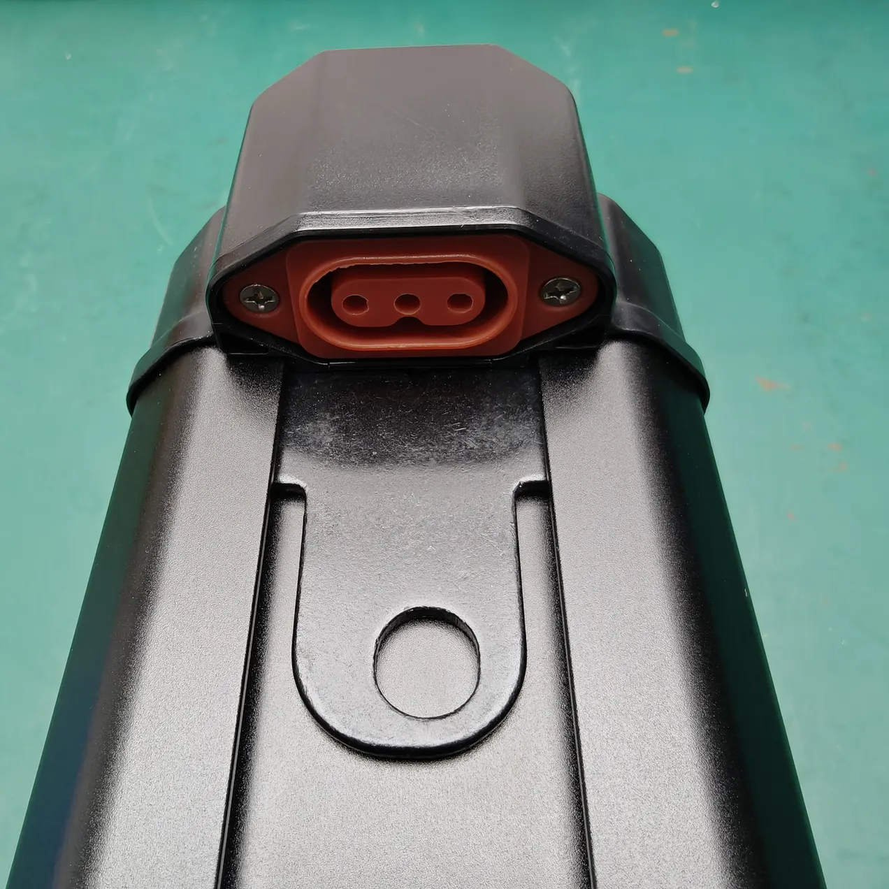 Close view of a red three-contact socket and mounting rail on a black battery case