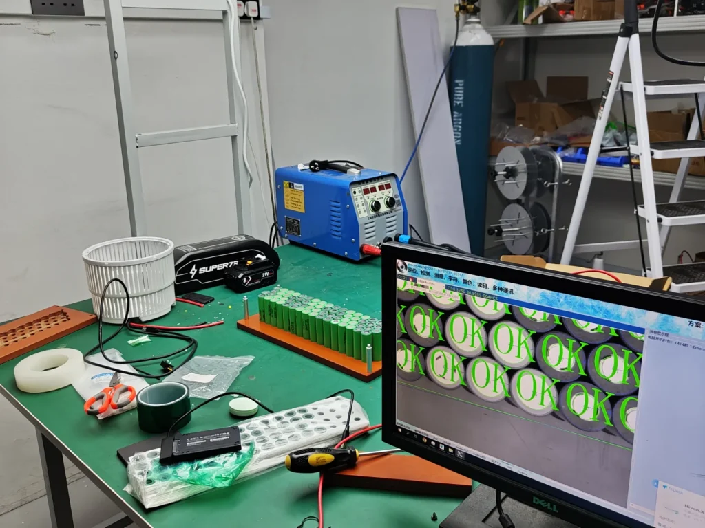 Workshop bench with cell layout and machine-vision review on a monitor