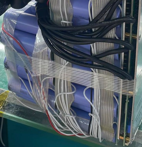 Clear tape crosses the blue cells, with white leads looped along the side.
