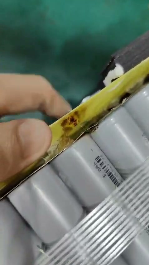 dark discolouration on the yellow layer beside a thin metal strip at the tops of grey-wrapped cells.