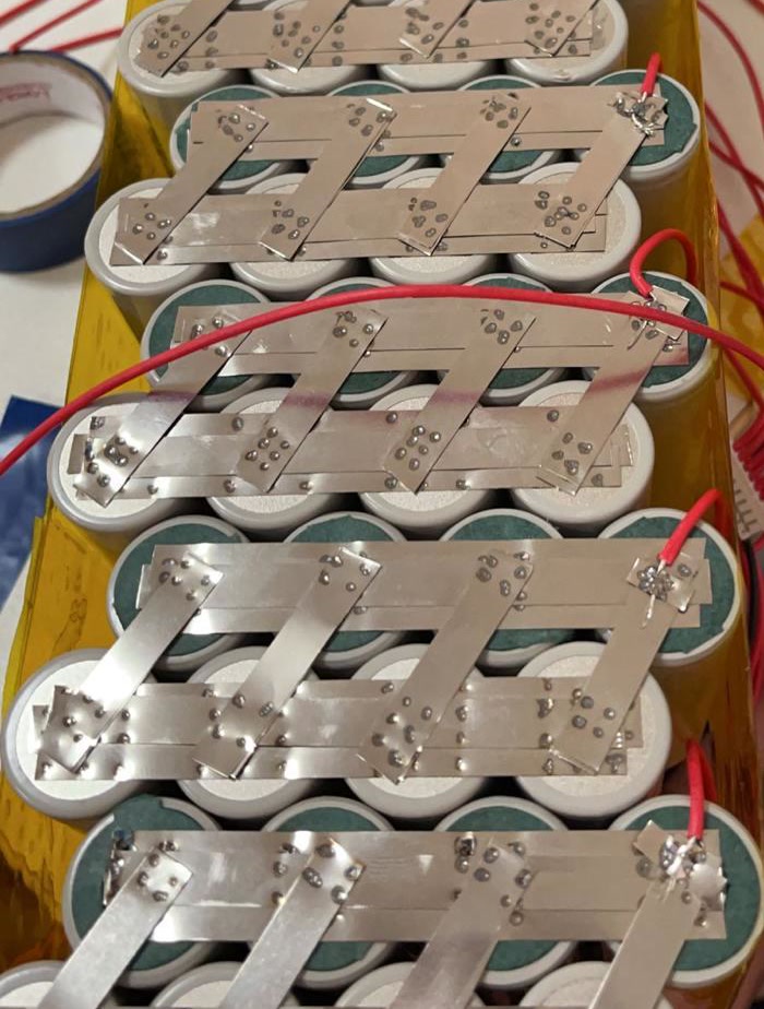 Red balance wires at soldered points on layered metal strips across the cell ends.