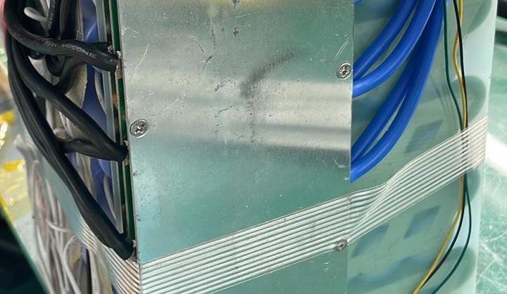 Clear tape crosses the BMS cover, with blue and black leads beside it.