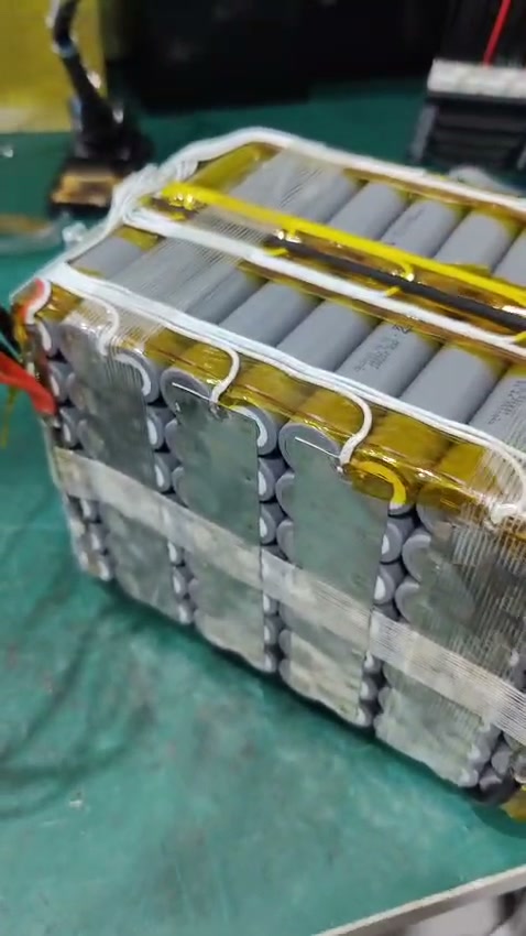 Grey-wrapped cells, yellow film and reinforced tape, with white leads running across the top and down to the strips.