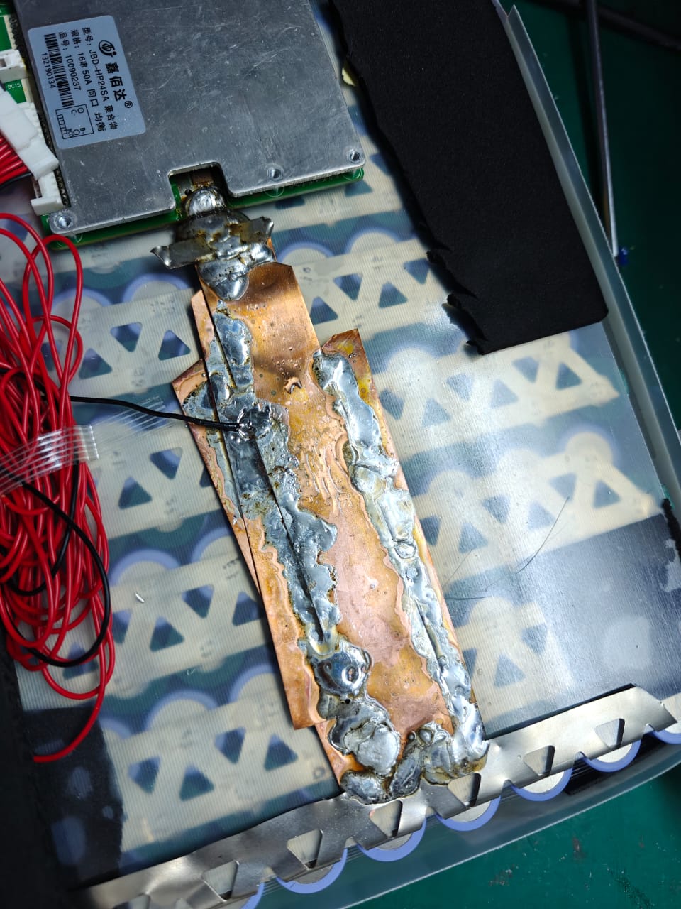 Overheated copper busbar and solder joints beside a battery management system