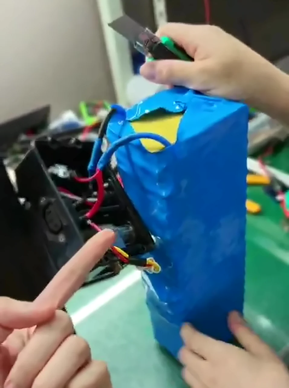 The same battery with its case open: a blue heat-shrink pack with the black connector housing wired straight into it