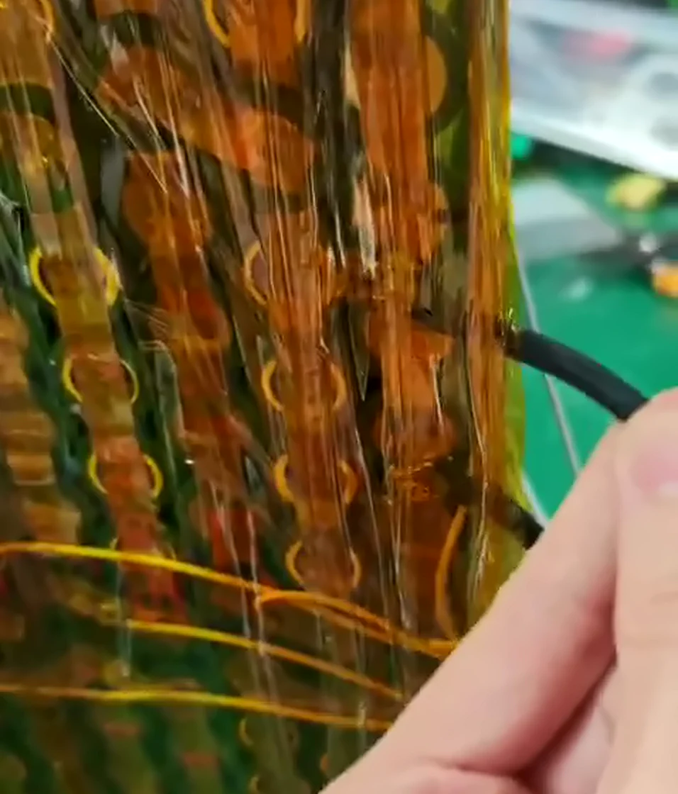 Close-up of cell ends under Kapton tape, a black lead entering from the right with its end among the nickel strips