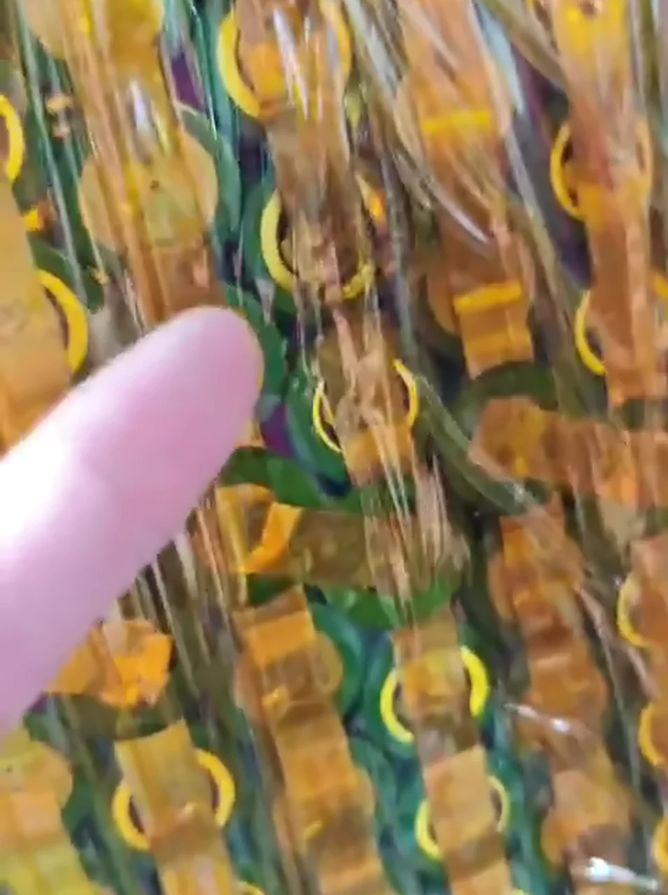 Thin nickel strips across green-wrapped cell ends under Kapton tape, a finger pointing