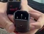 An uncapped three-pin charging connector held in a hand